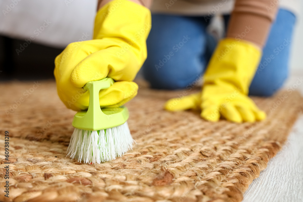 Housewife cleaning carpet with brush in bedroom, closeup