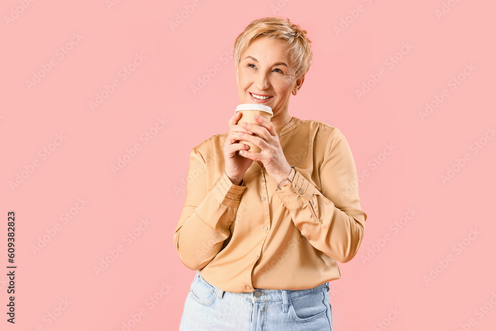 Dreaming mature woman with cup of coffee on pink background