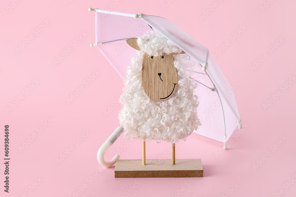 Creative composition with wooden toy sheep and mini umbrellas on pink background