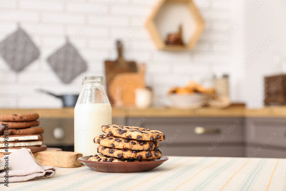 Cookies with chocolate and bottle of milk on table in kitchen