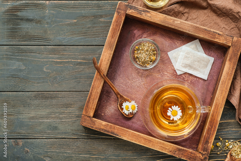 Cup of hot chamomile tea on dark wooden background