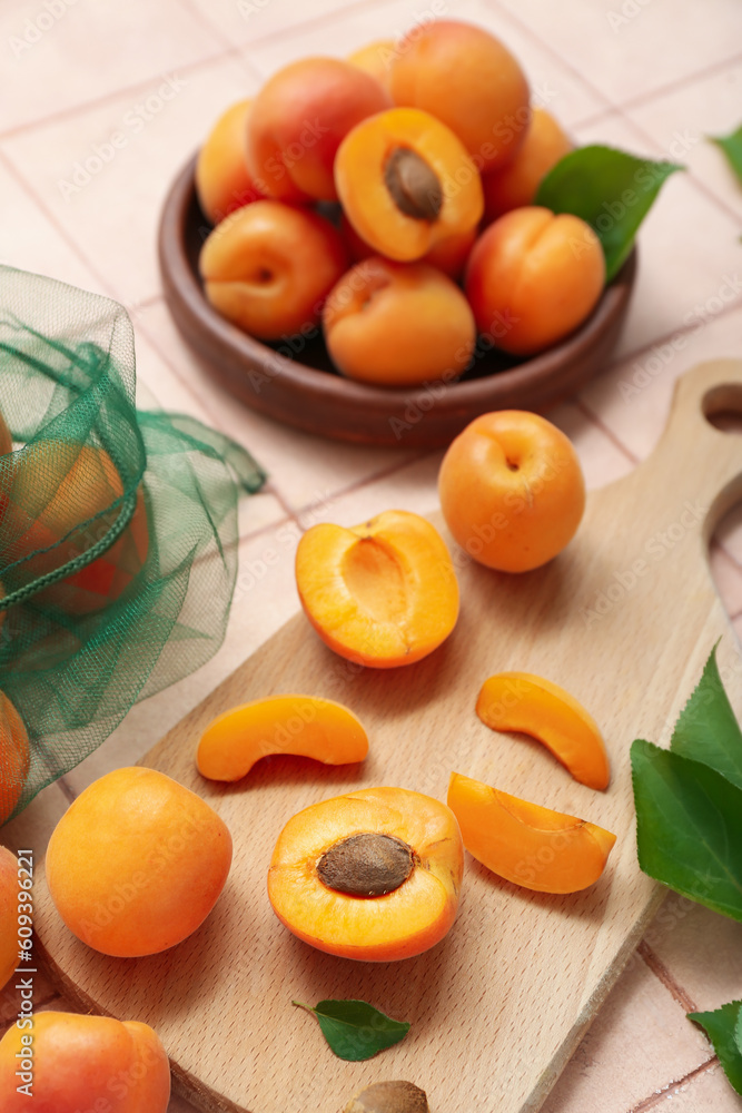 Board and plate with fresh apricots on pink tile background