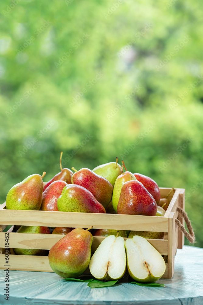 Red pear in wooden box over blur greenery background, Red pear in basket on green bokeh background.