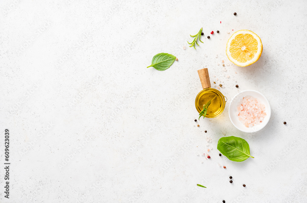 Various herbs and spices, oil in glass bowl and half of lemon on a white concrete background. Backgr