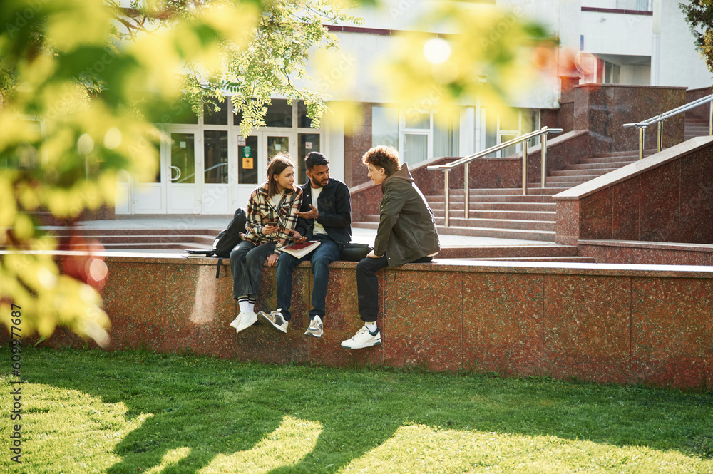 University building is behind. Young students in casual clothes are together outdoors