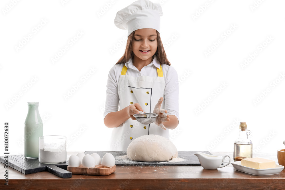 Little baker sprinkling flour onto dough on white background