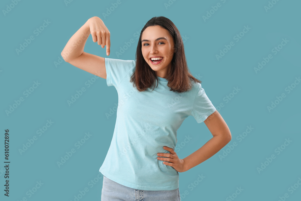 Young woman pointing at something on blue background