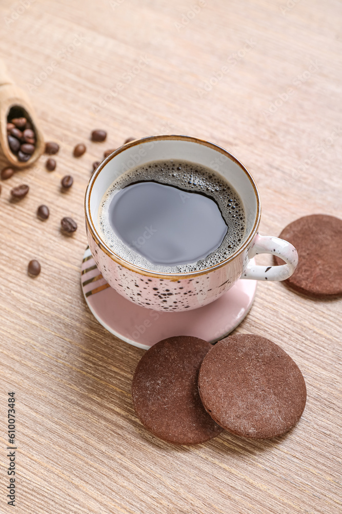 Drink coaster with cup of coffee and cookies on wooden table