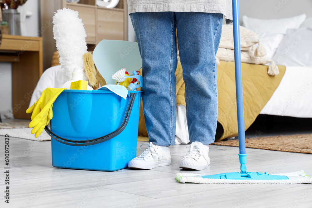 Housewife with cleaning supplies in bedroom