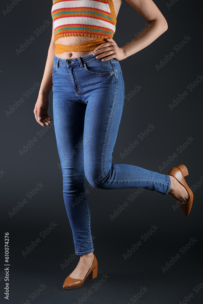 Young woman in skinny jeans on dark background