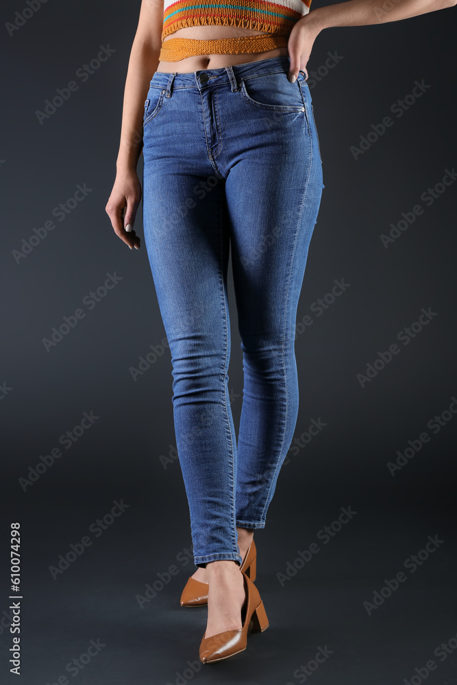 Young woman in skinny jeans on dark background