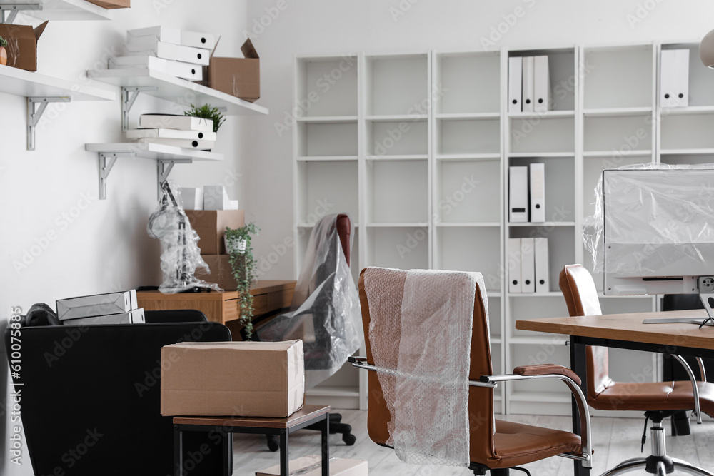 Interior of office with workplaces and cardboard boxes on moving day