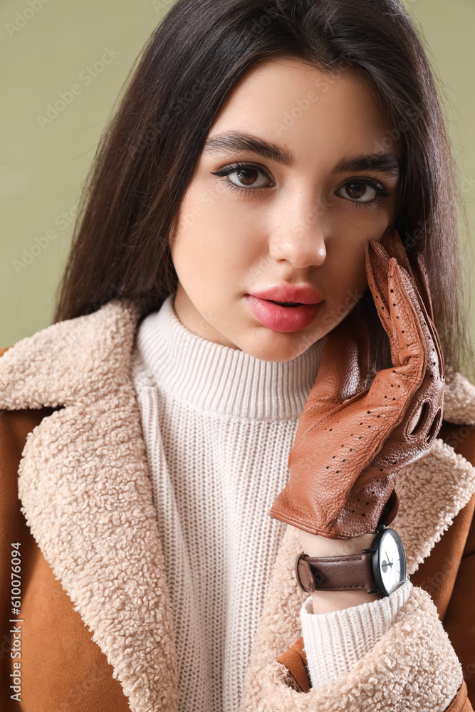 Stylish young woman in leather gloves on green background, closeup