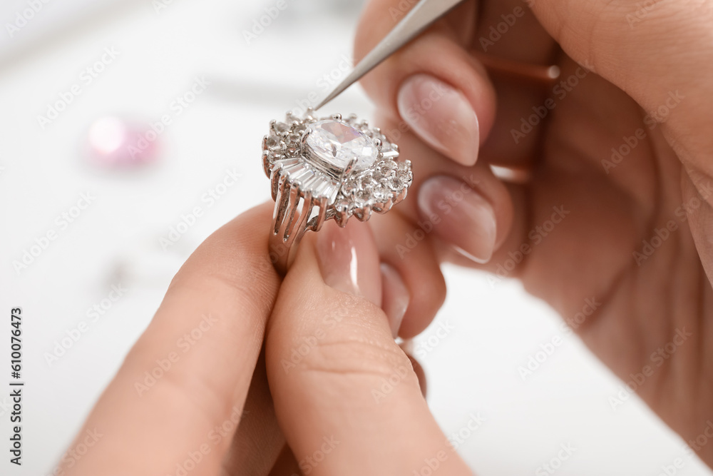 Female jeweler making ring on white table, closeup