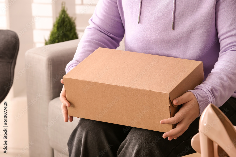 Woman holding box with shoes in room