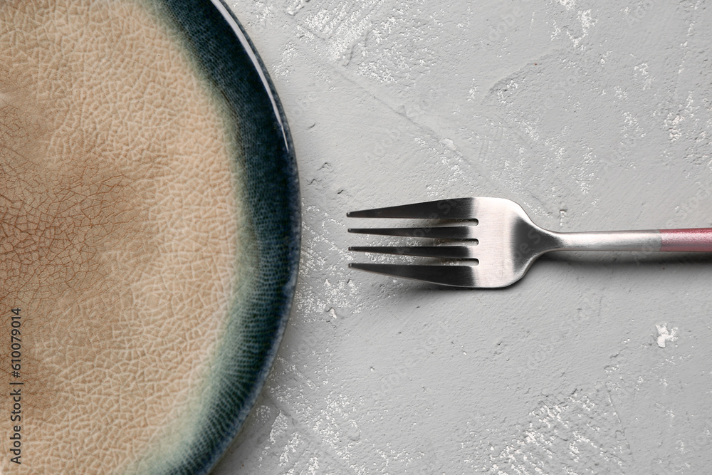 Plate with stainless steel fork on grey background