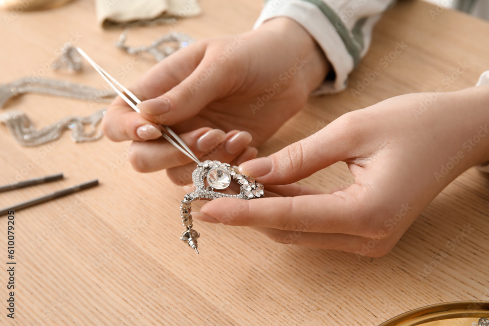 Woman cleaning beautiful earring at wooden table, closeup