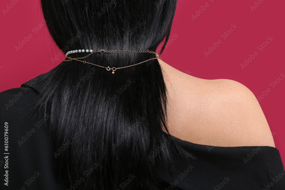 Beautiful young woman wearing golden necklace near red wall, back view