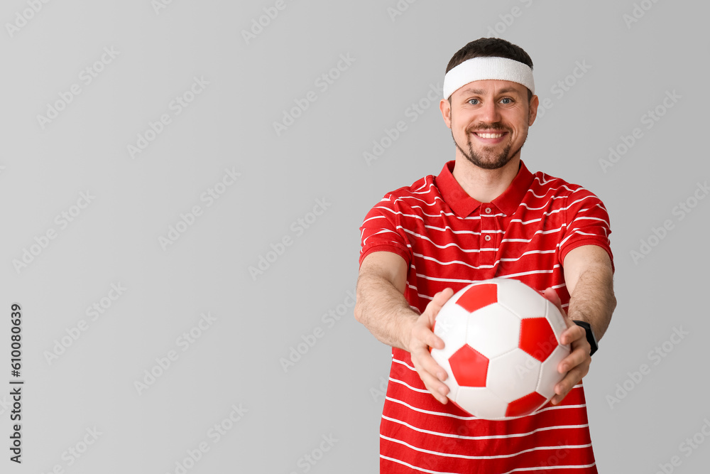 Happy man with soccer ball on light background