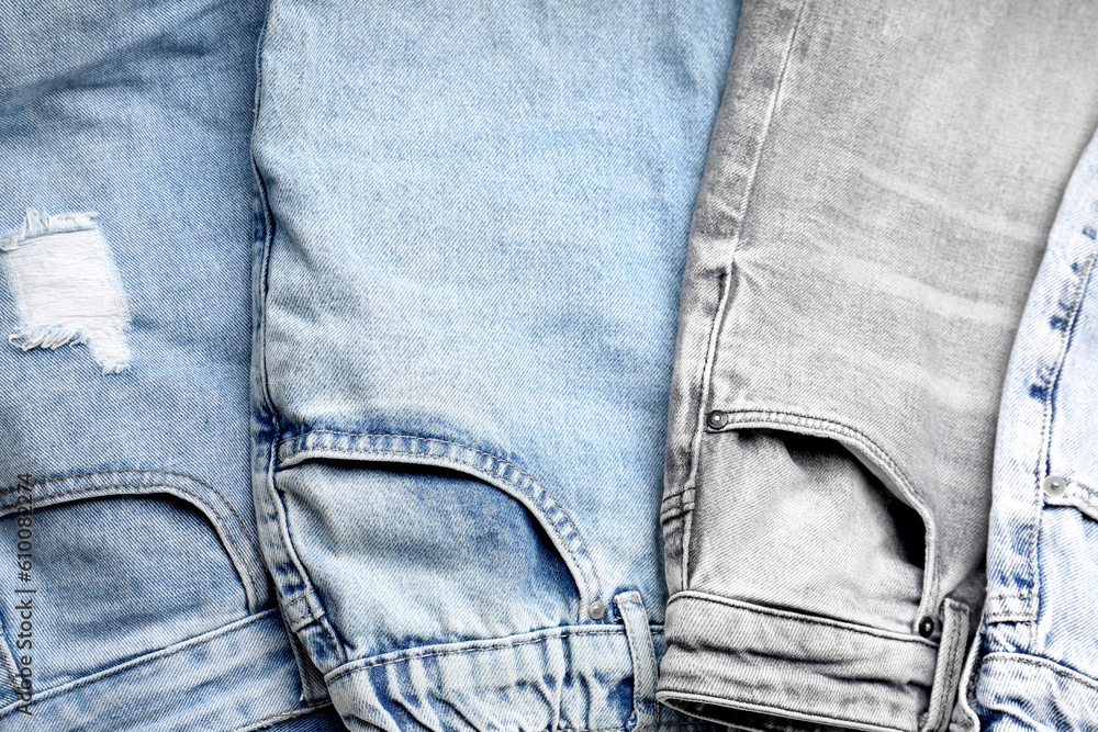 Different stylish denim jeans as background, closeup