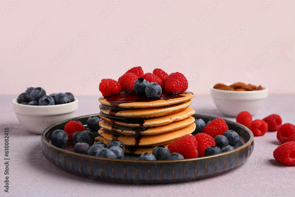 Plate with sweet pancakes, berries and nuts on pink background, closeup