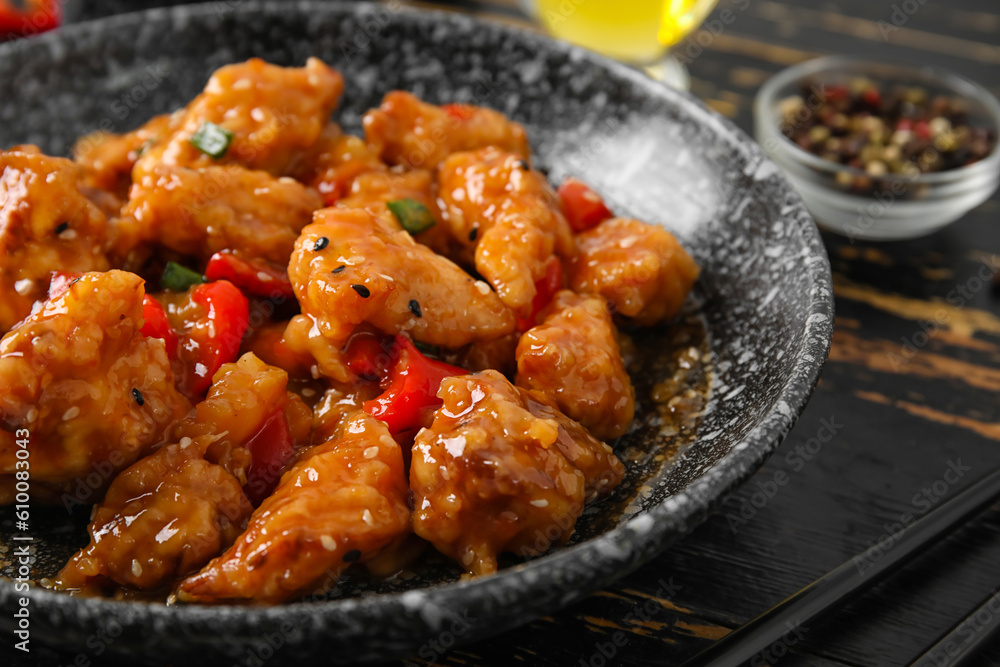 Bowl with tasty sweet and sour chicken on dark wooden background, closeup