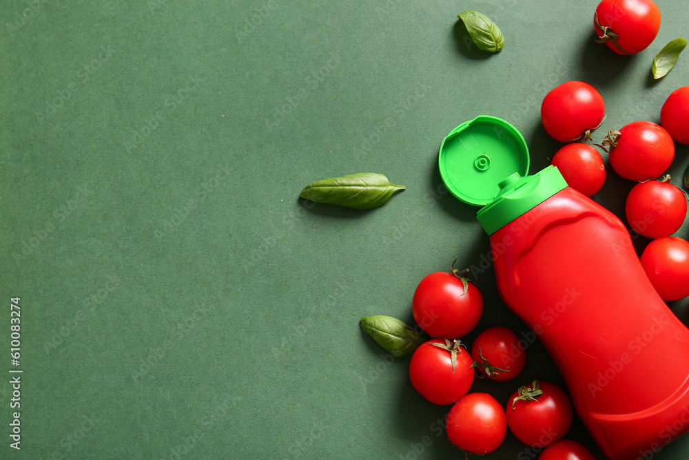 Bottle of ketchup and tomatoes on green background