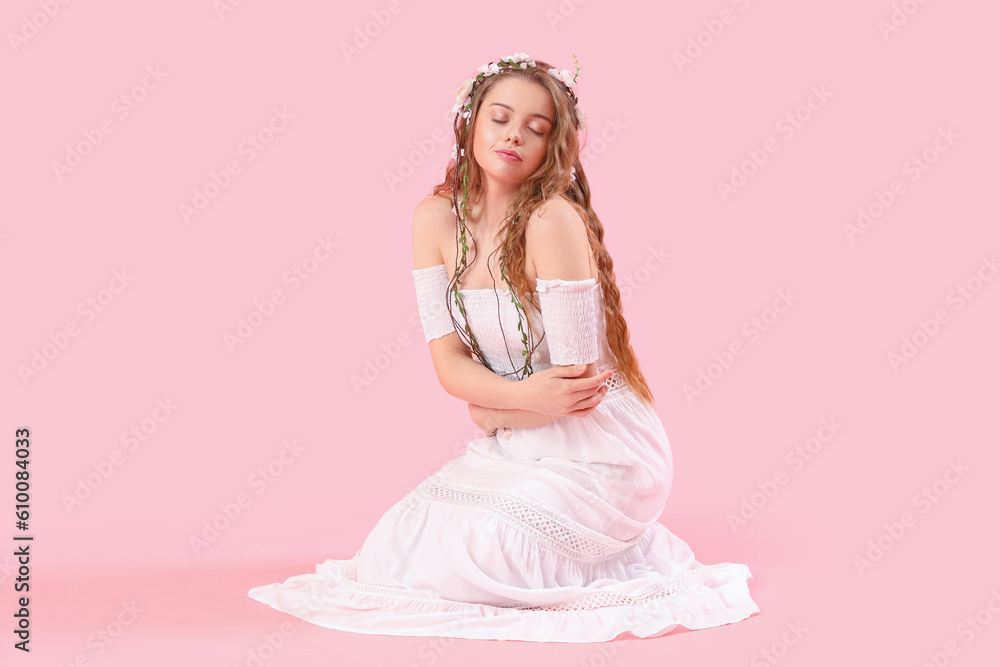 Beautiful young woman with flowers in her hair on pink background. Summer solstice