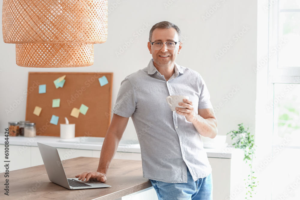 Mature man with eyeglasses and cup of coffee in kitchen