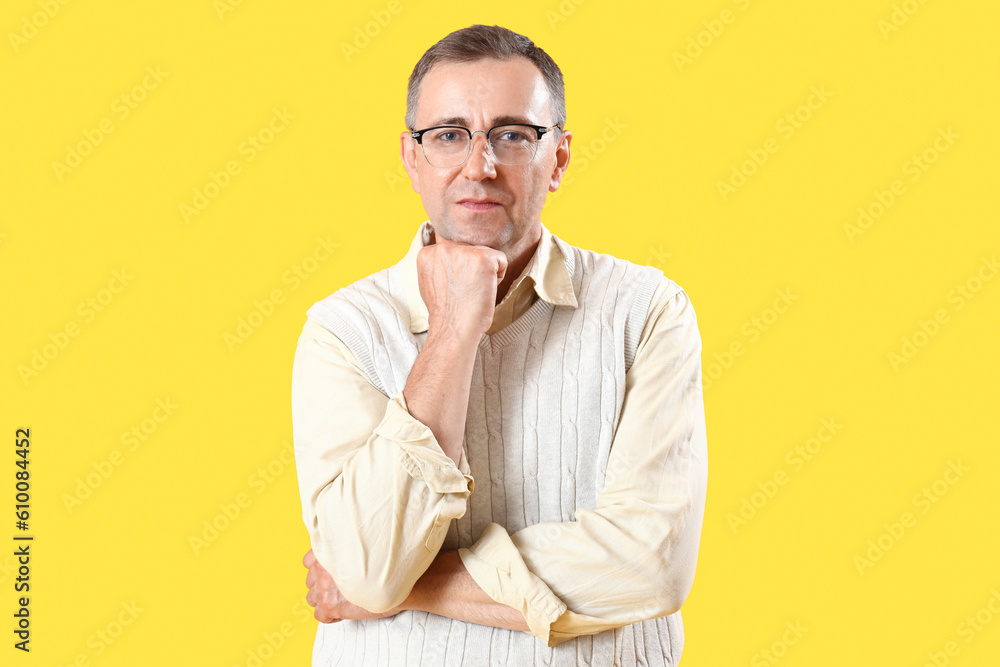 Mature man in eyeglasses on yellow background