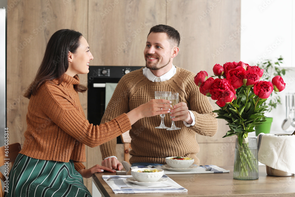 Happy engaged couple drinking wine in kitchen