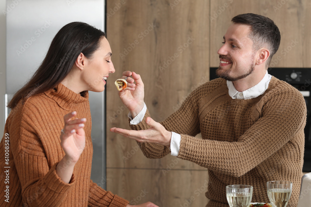 Happy engaged couple having dinner in kitchen