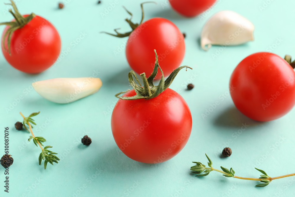 Ripe cherry tomatoes, thyme, garlic and peppercorn on turquoise background, closeup