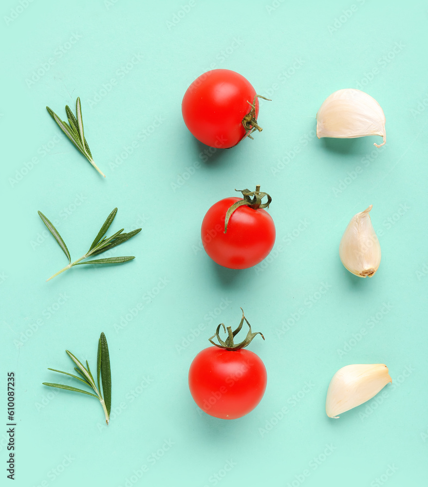 Composition with ripe cherry tomatoes, rosemary and garlic on turquoise background