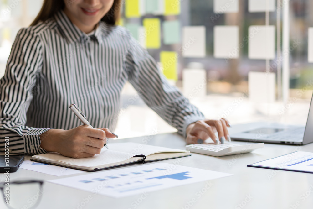 Businesswoman doing accounting work in the office analyzing charts in financial reports with a calcu