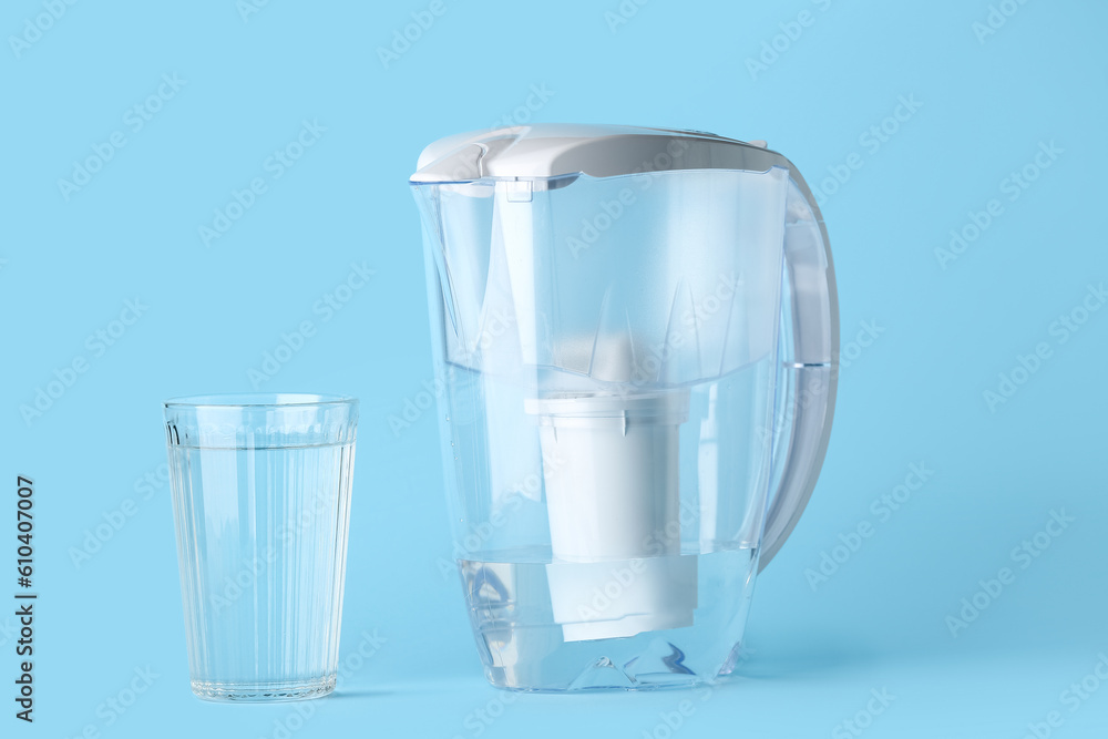 Water filter jug with glass on blue background