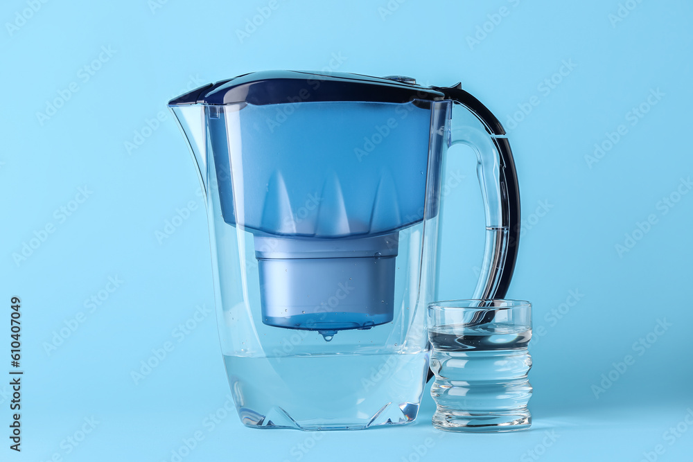 Water filter jug with glass on blue background