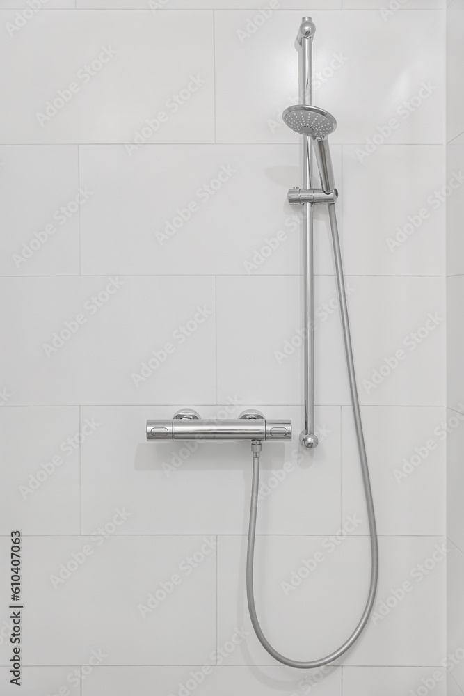 Mixer tap with showerhead on light wall in bathroom