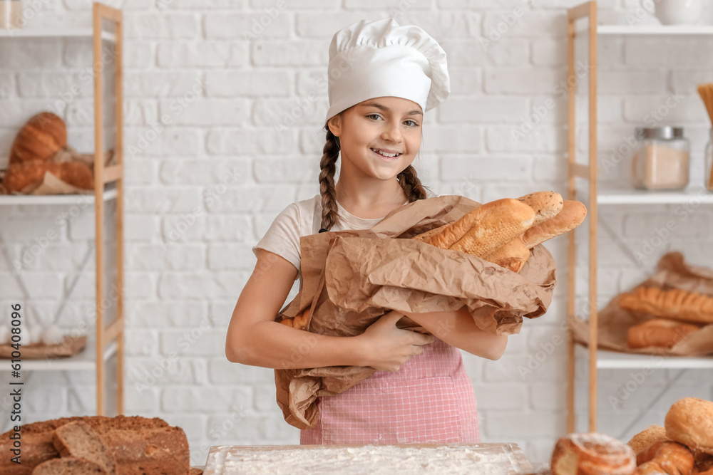 Little baker with fresh baguettes in kitchen