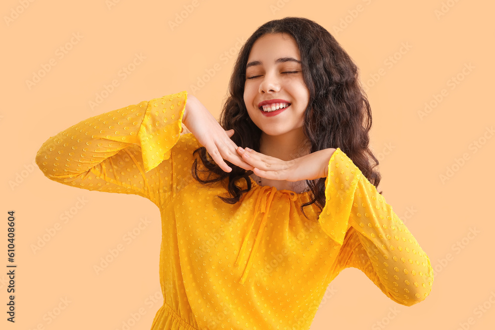 Teenage girl in yellow dress smiling on beige background