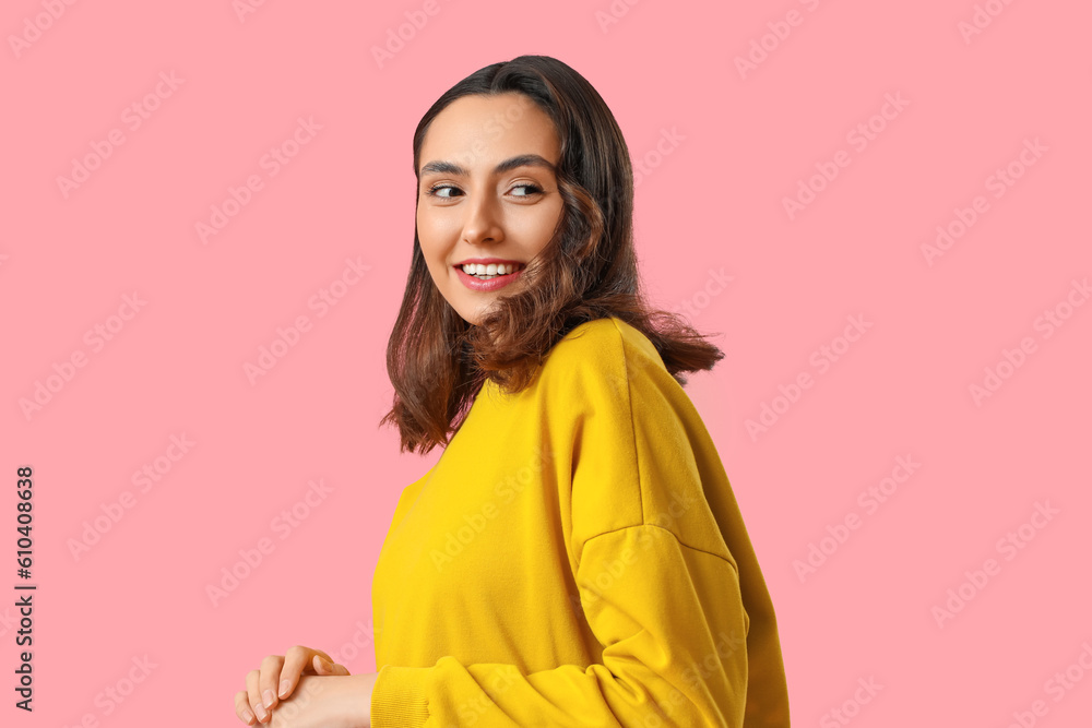 Young woman in yellow sweatshirt on pink background