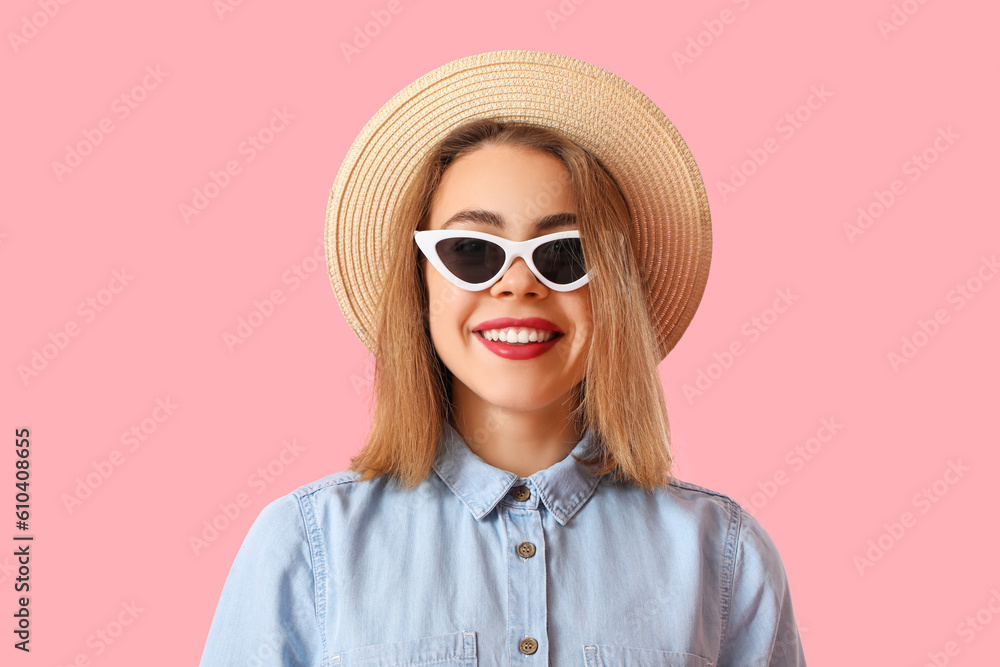 Young woman in hat and sunglasses on pink background, closeup