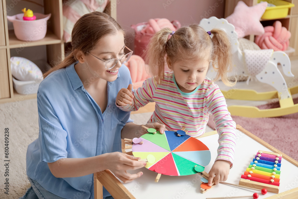 Mother and her little daughter playing matching game with clothespins at home