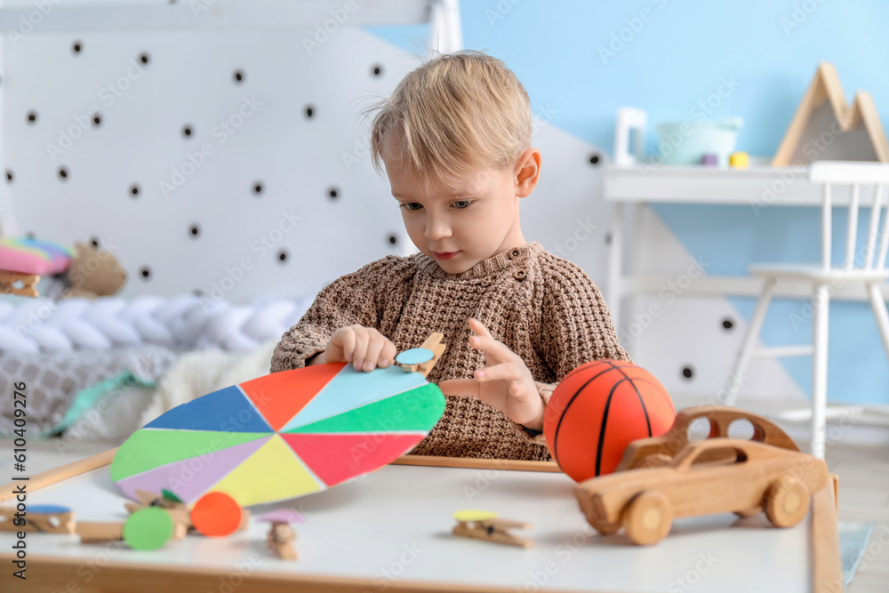 Cute little boy playing matching game with clothespins at home