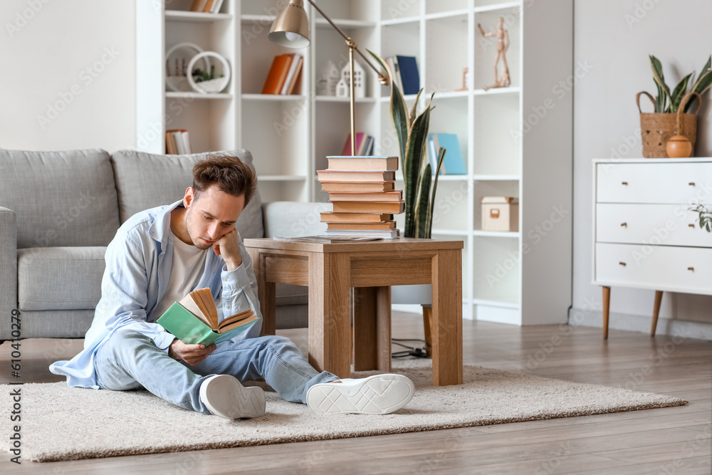 Young man reading book on floor at home