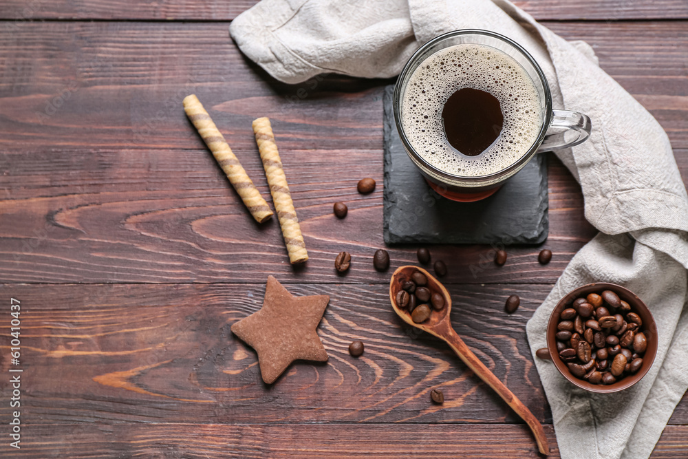 Drink coaster with cup of coffee, sweets and beans on wooden table