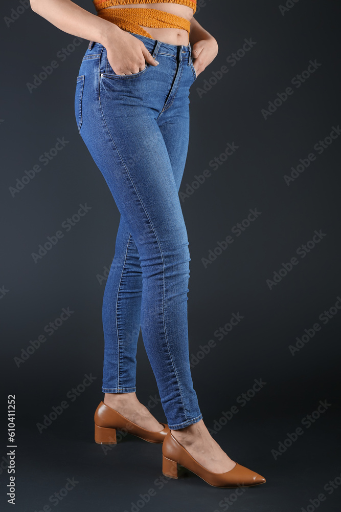 Young woman in skinny jeans on dark background