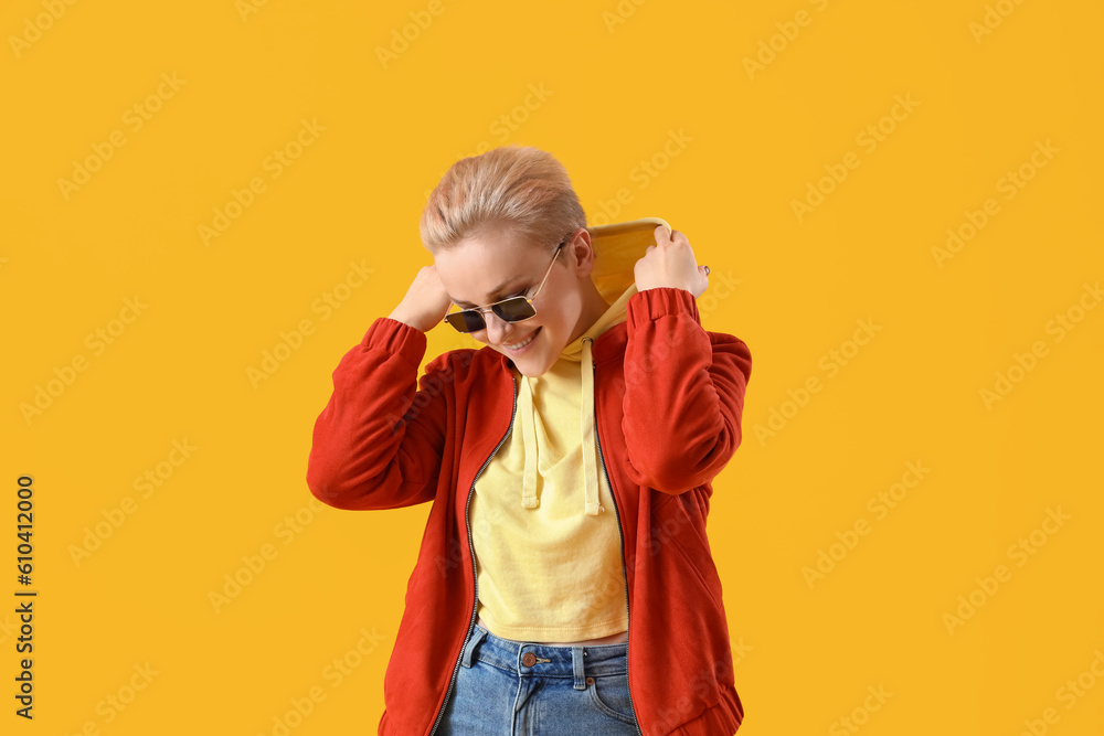 Young woman in sunglasses on yellow background