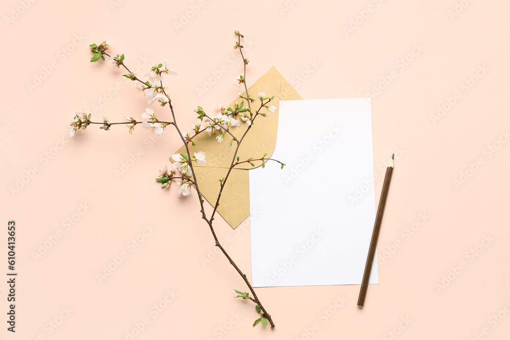 Blooming tree branch with white flowers, blank paper sheet, pencil and envelope on beige background