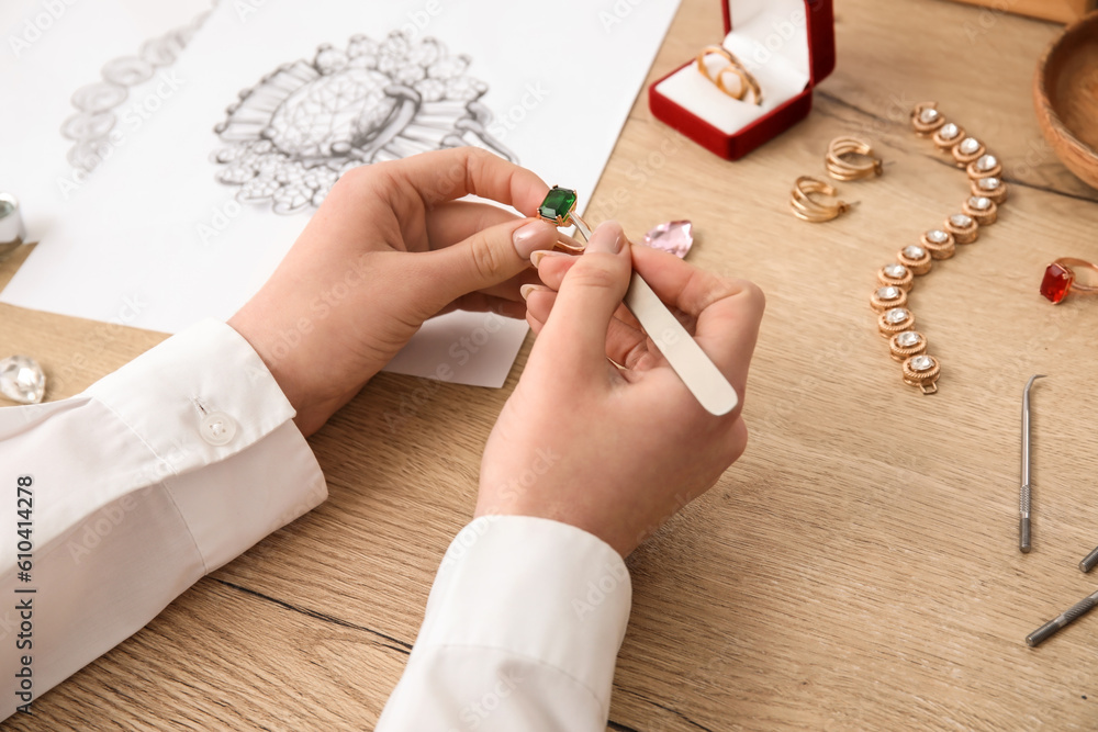 Female jeweler making ring on wooden table, closeup